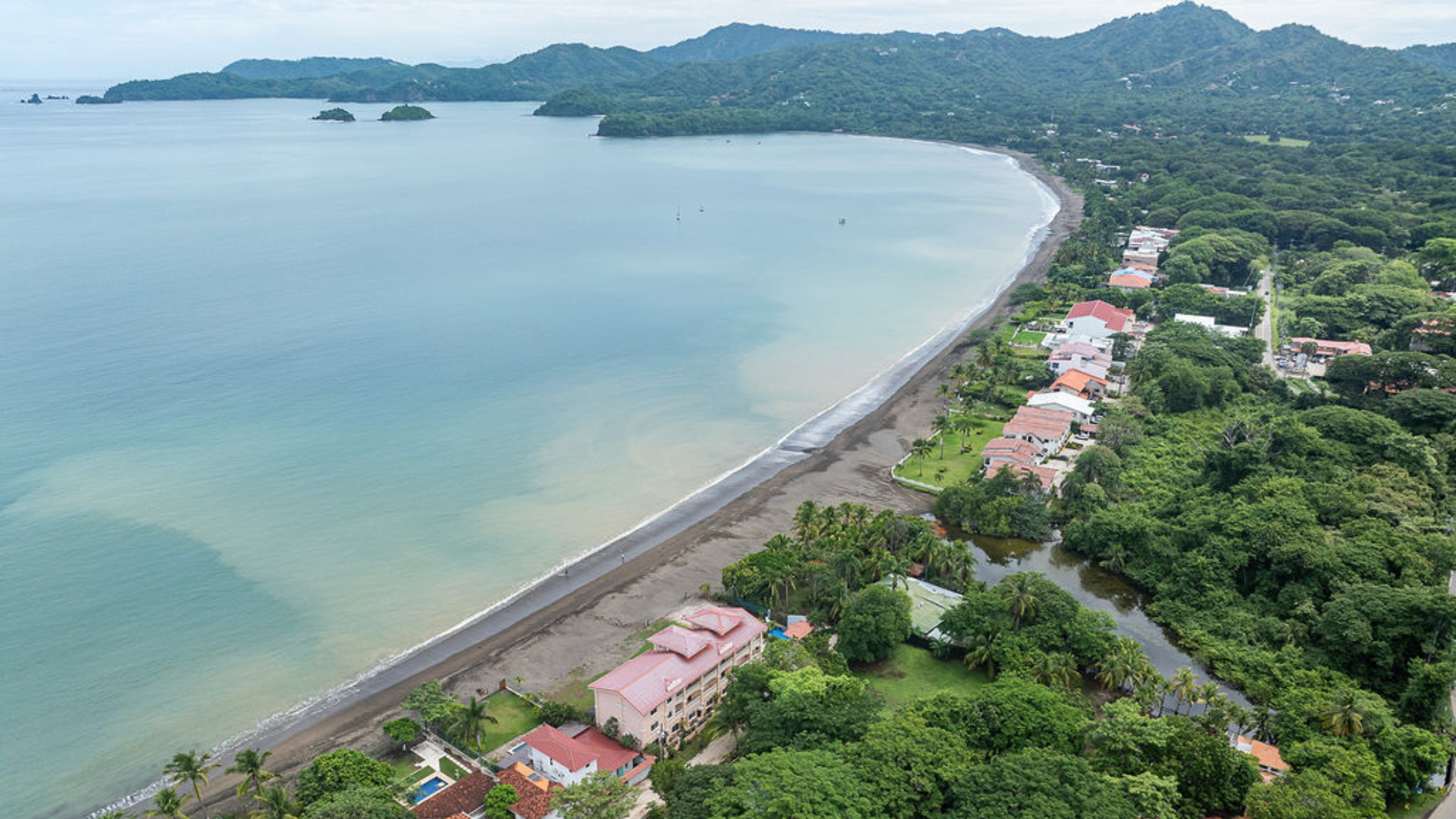 Playa Potrero Costa Rica Real Estate community with beachfront homes, calm bay, and lush green hills.