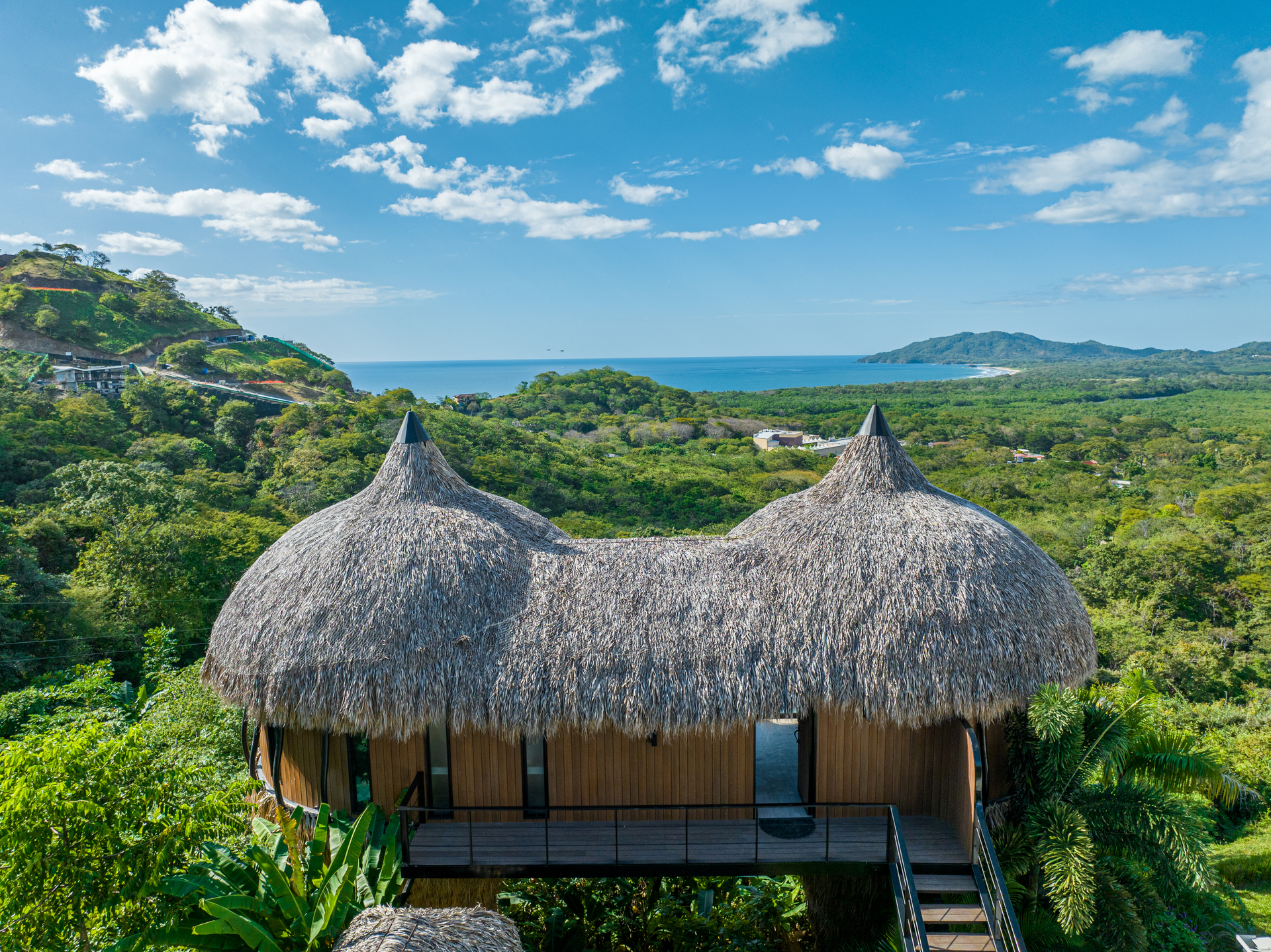 Cocoon villa with twin thatched roofs above jungle canopy, living in Guanacaste Costa Rica