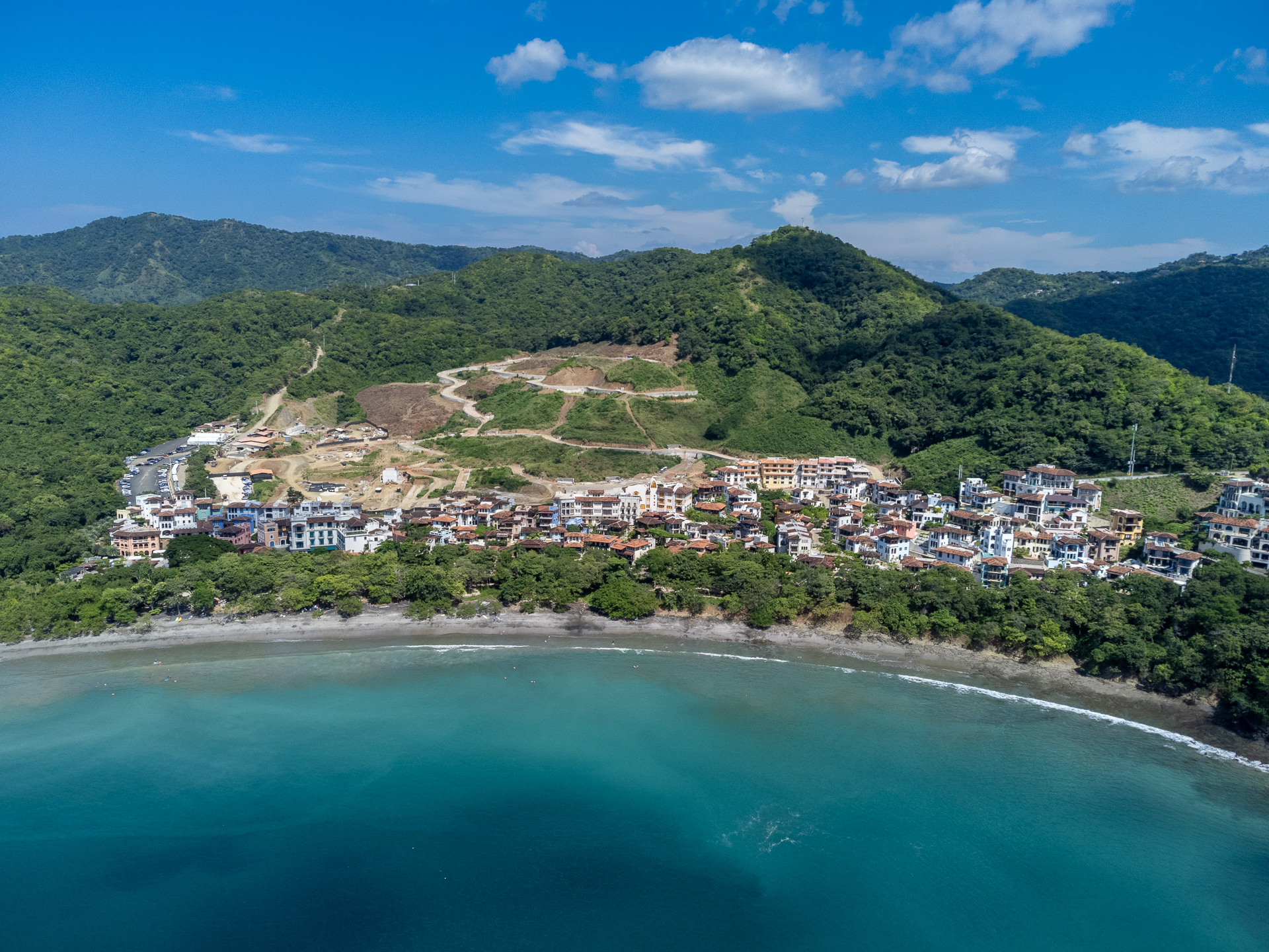 Aerial view of Las Catalinas Beach Town and Playa Danta, showing coastal homes, turquoise water, and surrounding green hills.