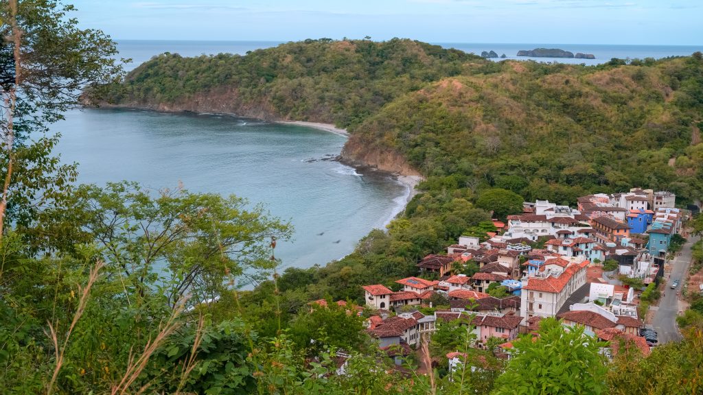 Hillside view overlooking Las Catalinas Costa Rica, with Playa Danta’s turquoise bay and the town’s red-roof homes below.