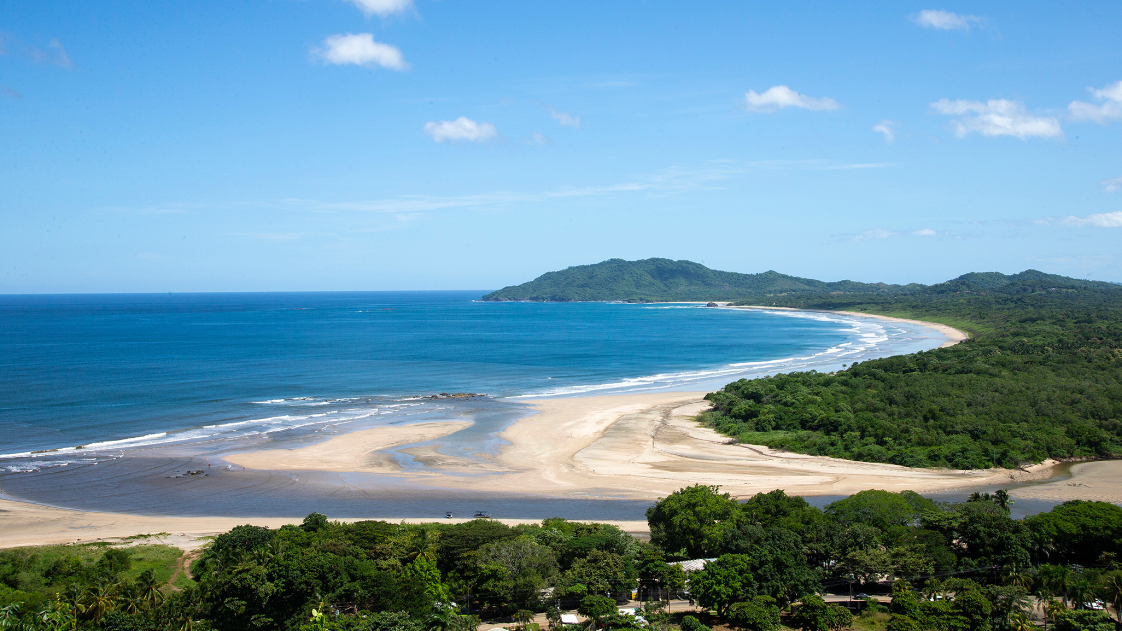 Aerial view of Playa Grande Costa Rica with turquoise ocean, golden sand, and lush green forest.
