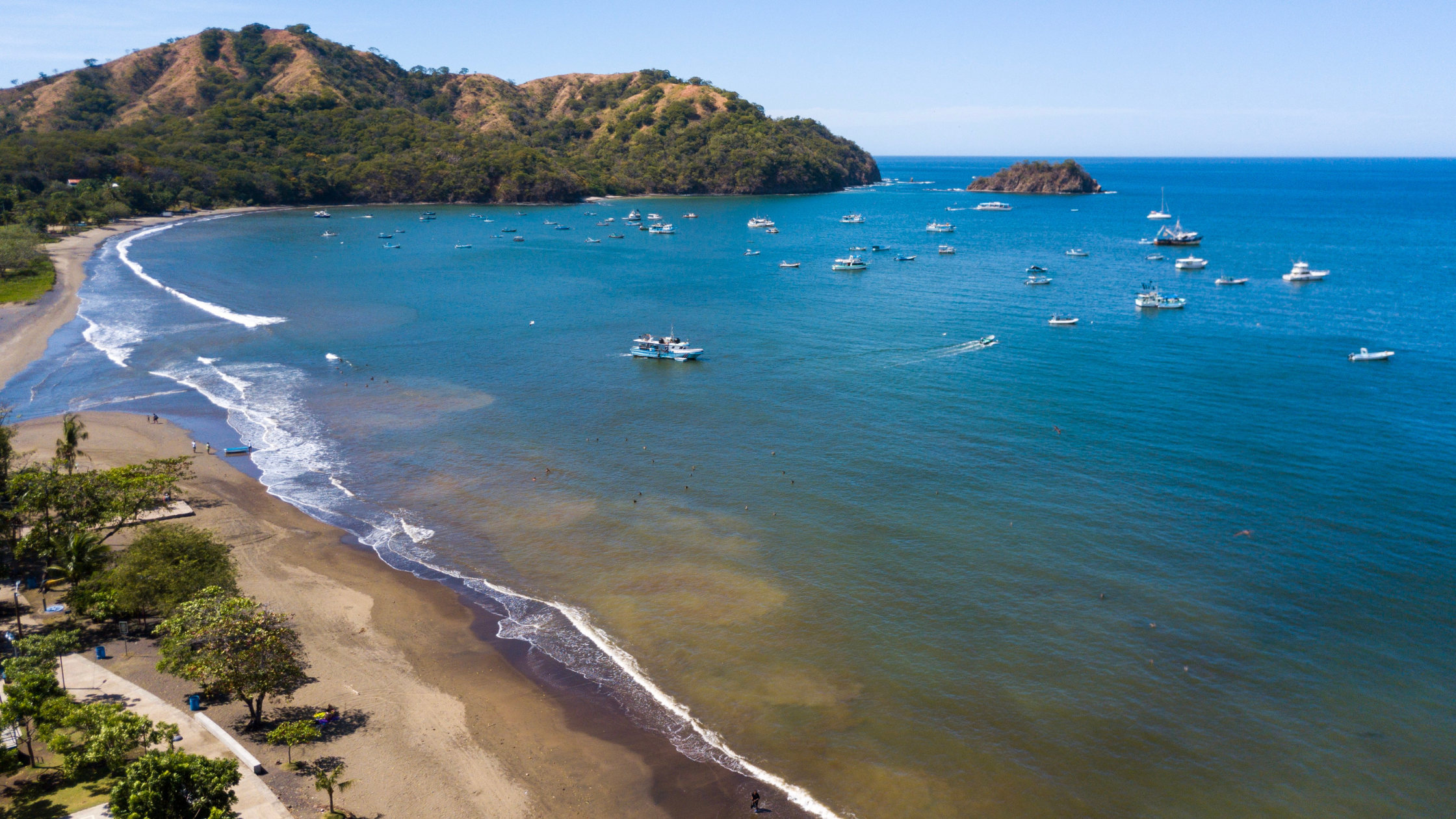 Aerial view of Playas del Coco Costa Rica with golden beach, calm bay, and anchored boats