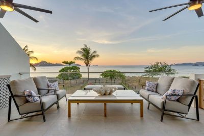 Oceanfront terrace with modern seating, palm trees, and sunset views at Villa Ballena, Playa Potrero