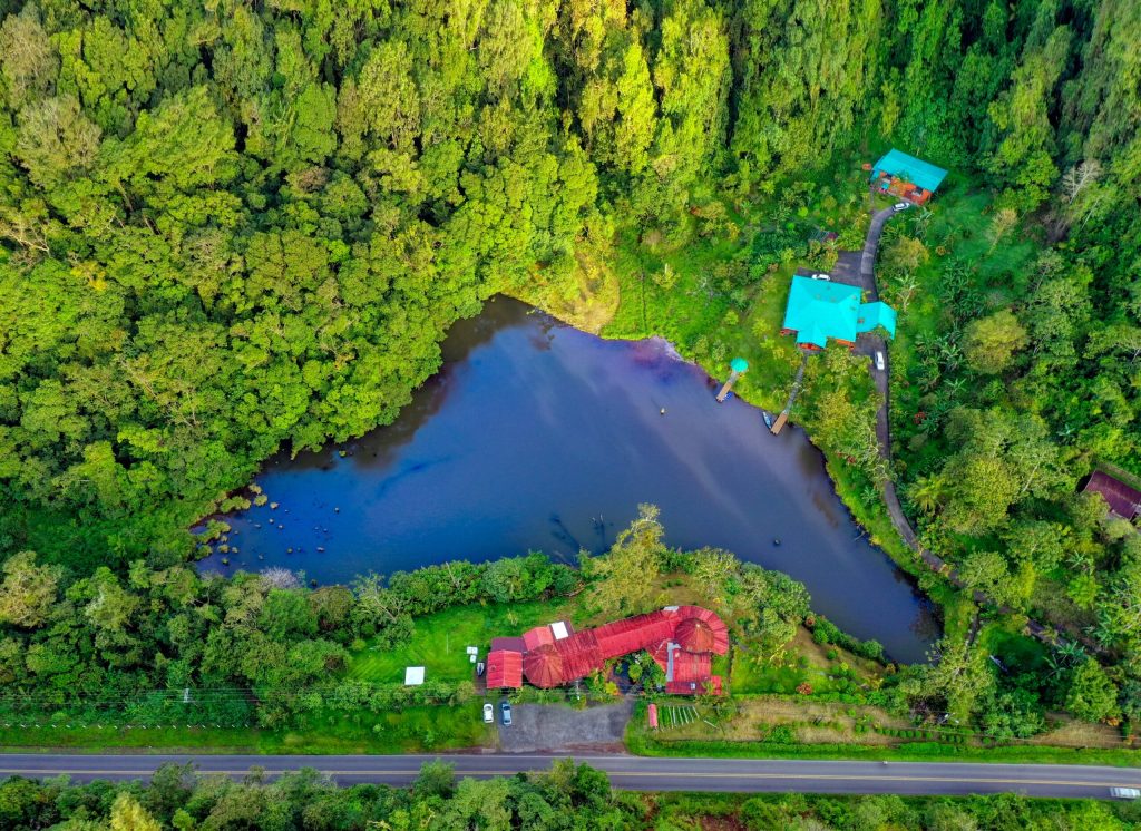 Aerial view of Lucky Bug in Nuevo Arenal, showing the private lake, surrounding forest, and main buildings.