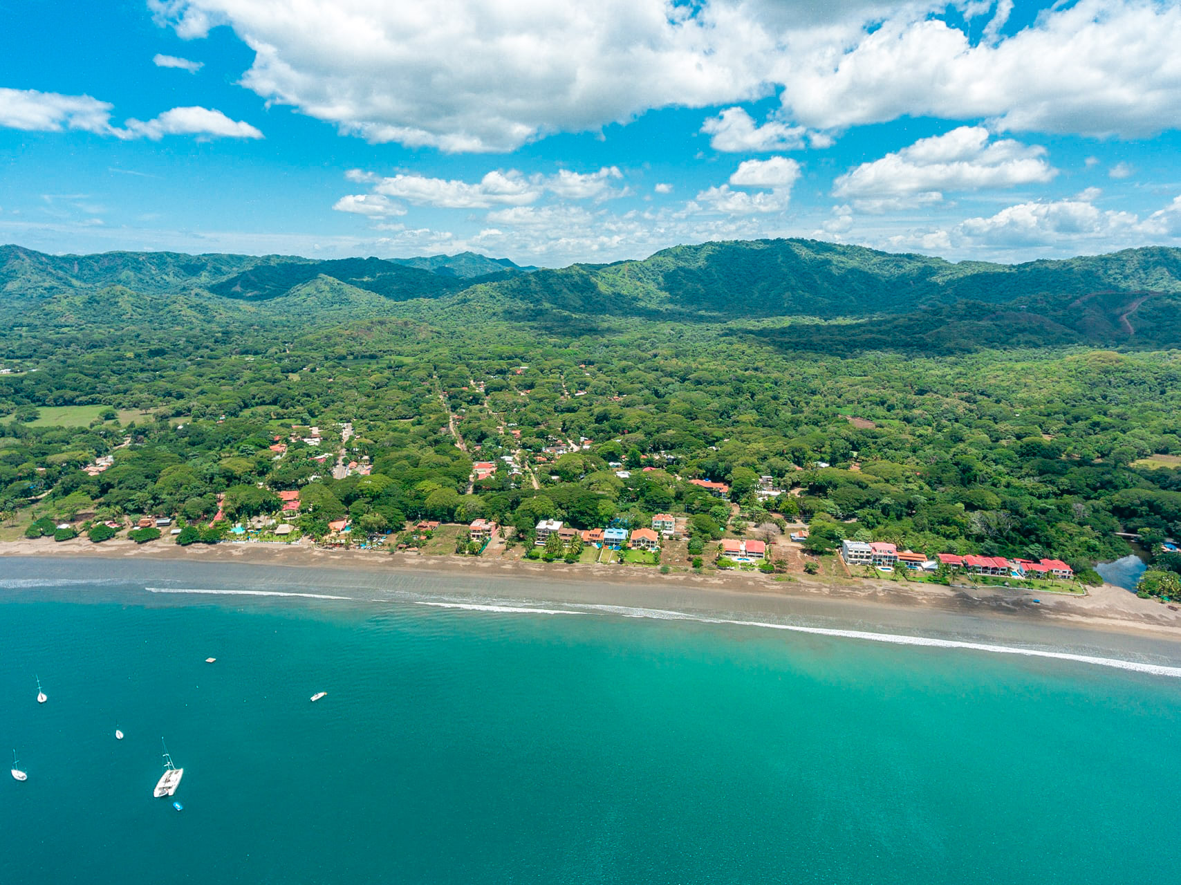 Aerial view of Surfside Playa Potrero Costa Rica with beachfront homes and lush green hills.