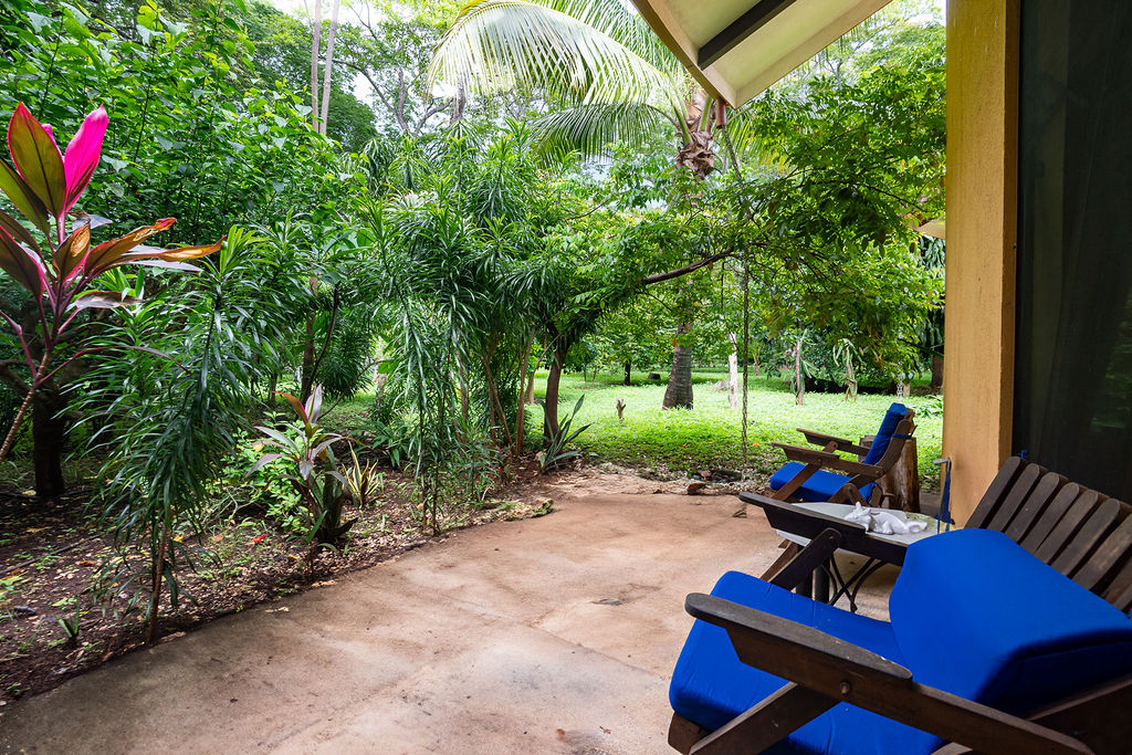 Casa Tortuga covered patio with blue chairs overlooking tropical garden and lawn – Costa Rica Real Estate CR