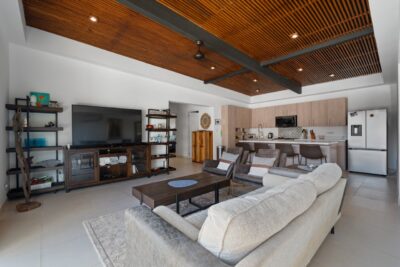 Modern open-concept living area at Casa Wish You Were Here in Tamarindo with wood ceiling, kitchen island, and lounge seating