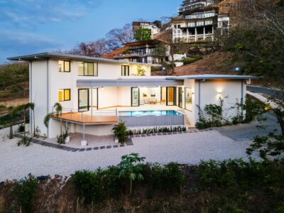 Casa Zoul, a modern hilltop luxury home with a pool, expansive decks, and floor-to-ceiling windows overlooking the tropical landscape.