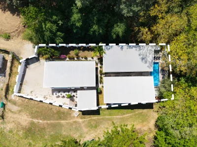 Aerial view of Three Mermaids Surfside Playa Potrero showing three private villas, gated layout, and central pool area near the beach.