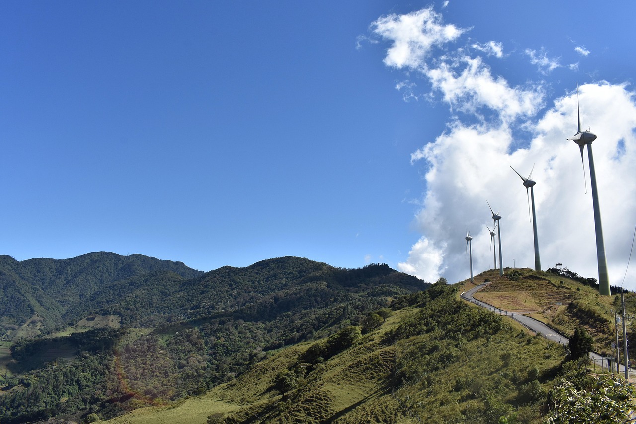 Wind turbines on a mountain ridge in Costa Rica with blue skies and clouds.