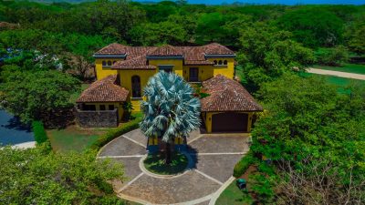 Casa Miraflores exterior with colonial design, clay-tile roof, and silver Bismarck palm in Hacienda Pinilla