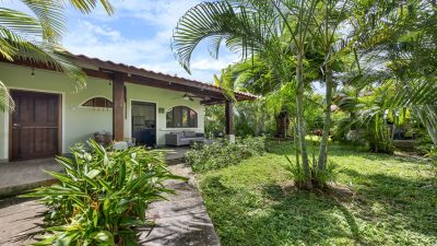 Exterior view of Casa Paloma in Villaggio 2, showing the covered patio, garden walkway, and lush tropical landscaping.