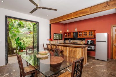 Open kitchen and dining area at Cornett Retreat Playa Grande with wood cabinetry, island bar, and garden access in Costa Rica