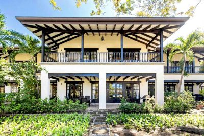Two-story townhome exterior with balcony, wooden roof, and tropical landscaping in Hacienda Pinilla, Costa Rica Real Estate Cr