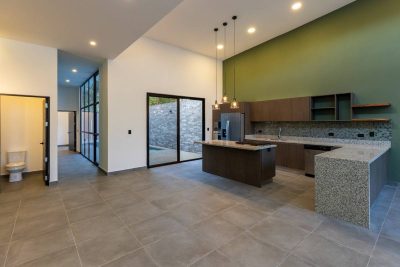 Modern kitchen interior in Luxury Beach House Playa Potrero with island, high ceilings, and sliding doors in Guanacaste.