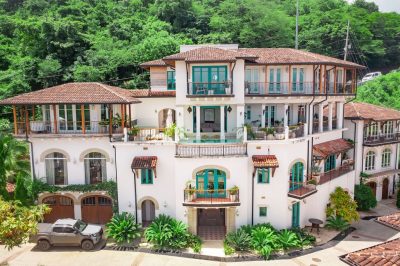 Villa Santorini Las Catalinas exterior with balconies, arched windows, and lush tropical landscaping in Costa Rica