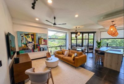 Spacious living room at La Perla #141 Tamarindo with modern décor, large windows, and balcony views