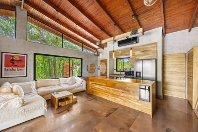 Open living area at Villa Stipanov Tamarindo with wood ceilings, kitchen island, and garden views through large windows
