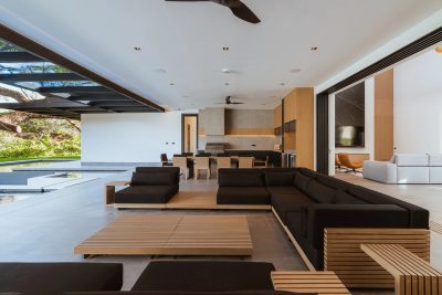 Modern open-plan living area with sofas, wood accents, and pool access at Los Almendros 38 Hacienda Pinilla | Costa Rica Real Estate CR