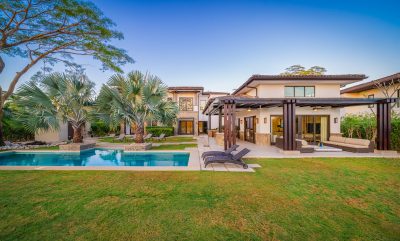 Backyard view of La Dulce Vida 5 in Hacienda Pinilla with pool, terrace, lounge seating, and tropical landscaping | Costa Rica Real Estate CR