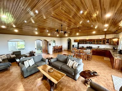 Open-concept living room and kitchen with wood ceilings, natural finishes, and spacious seating in a Lake Arenal luxury estate.