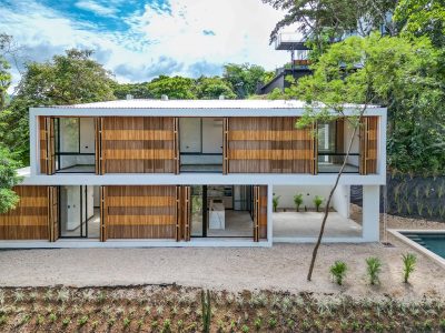 Modern tropical two-story home Casa Sabor Amar with wood panel accents, large glass doors, and forest surroundings in Costa Rica