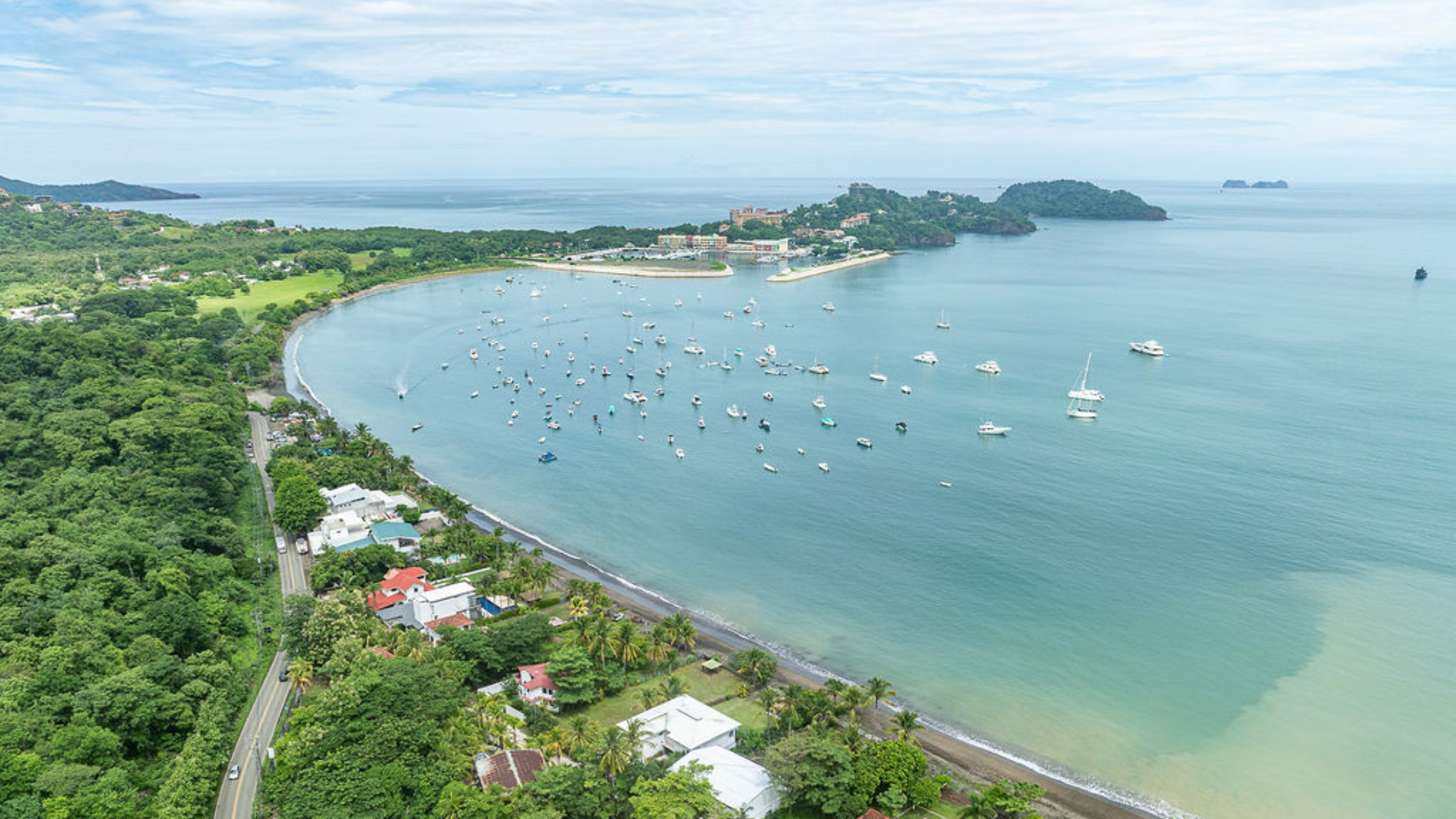 Aerial view of Surfside Potrero beachfront real estate along Playa Potrero, showing homes, shoreline, and calm Pacific waters