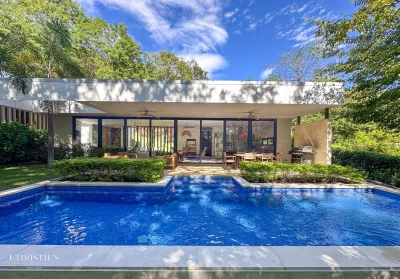 Modern poolside home at Casa Ruso in Senderos Tamarindo with covered terrace, glass doors, and lush tropical landscaping