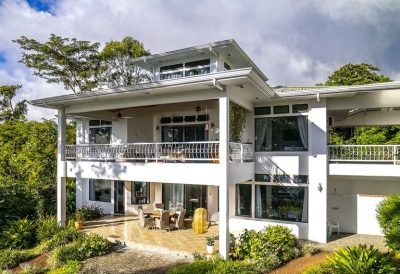 Two-story white villa with covered terraces, large windows, and surrounding greenery at Villa Corazon Lake Arenal, Costa Rica lakefront