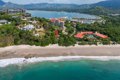 Aerial view of Villa Margarita Playa Flamingo showing red tile roof, surrounding greenery, and nearby Flamingo Marina and bay.
