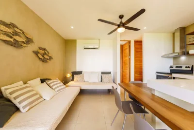 Open-concept living area with sofa beds, wood dining table, and kitchen in Terra Condos Unit 5 Tamarindo