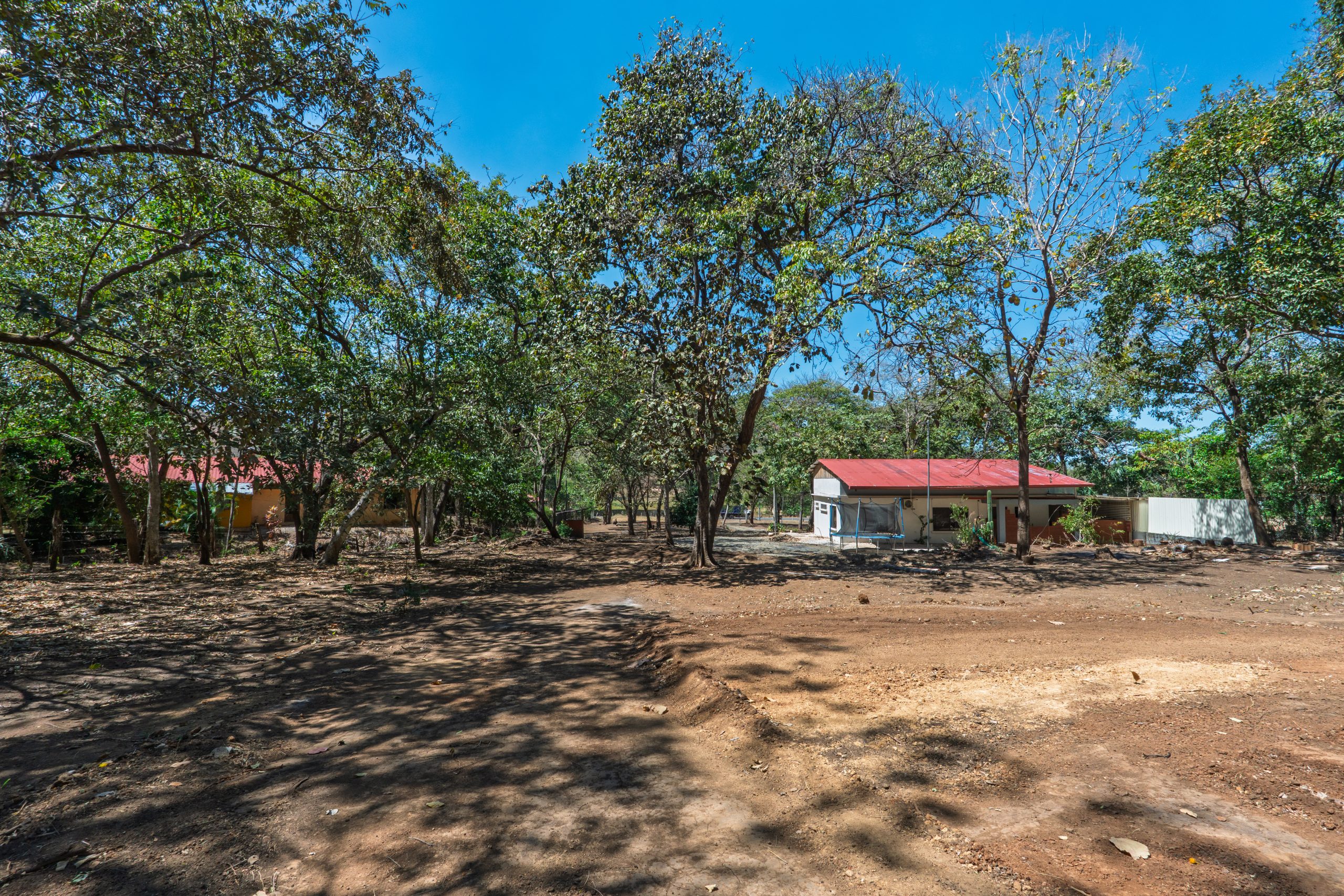 Wide interior view of Flamingo Lot in Playa Flamingo, Costa Rica with existing home and mature trees