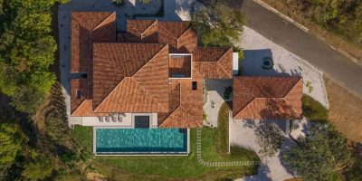 Aerial view of tiled-roof villa with rectangular infinity pool and landscaped yard in Mar Vista, Flamingo