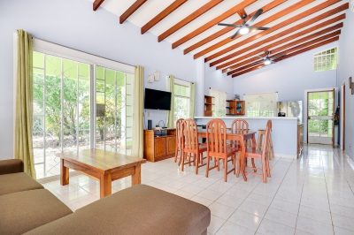 Open living and dining area inside Casa Arbol Surfside Potrero with wood-beam ceiling and garden-view doors — Surfside Potrero real estate
