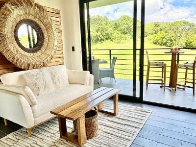 Modern Tamarindo Apts living room opening to terrace with green field views in Tamarindo, Costa Rica walk to beach condo