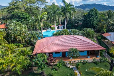 La Dolce Vita Potrero villa exterior with pool, tropical gardens, and mountain backdrop in gated community Potrero
