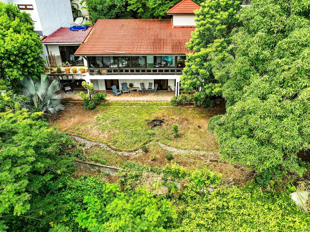 Casa Moon rear exterior with terrace, hillside yard and tropical trees in Playa Flamingo real estate