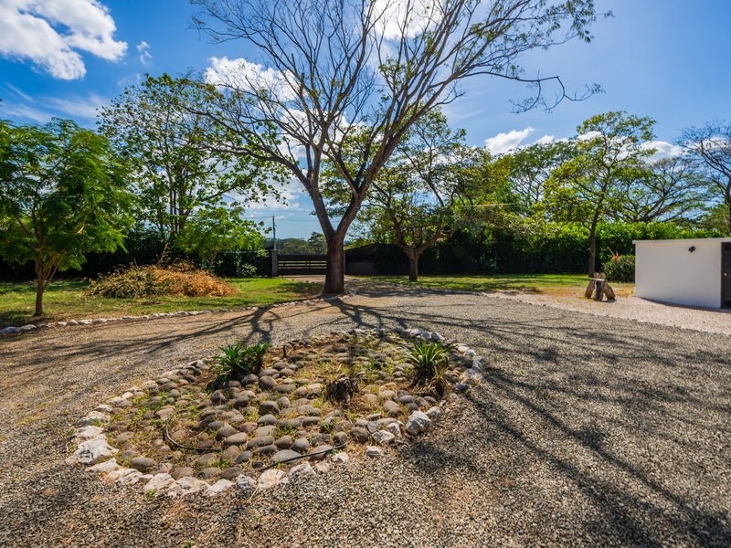 Finca Panama landscaped yard with mature trees and gravel driveway in Tamarindo, suited for furnished property with development potential