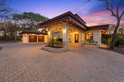 New Three Bedroom Spanish Colonial Home exterior with driveway and garage in Hacienda Pinilla Costa Rica at sunset
