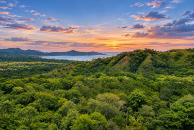 Golden sunset over a coastal bay, surrounded by rolling green hills and dense tropical forest.Image Title: Twin Sisters Pacific Sunset Panorama