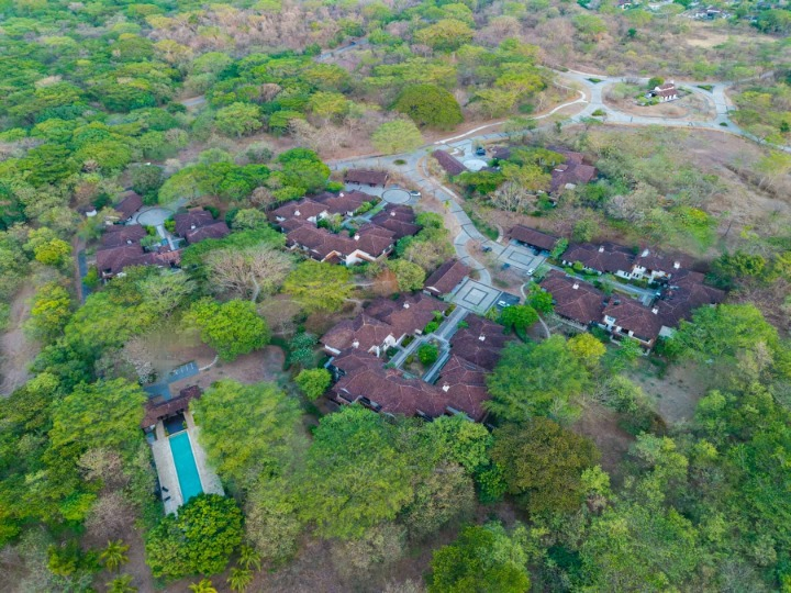 Aerial view of Los Malinches 22 within Hacienda Pinilla showing homes, trees, roads, and shared amenities