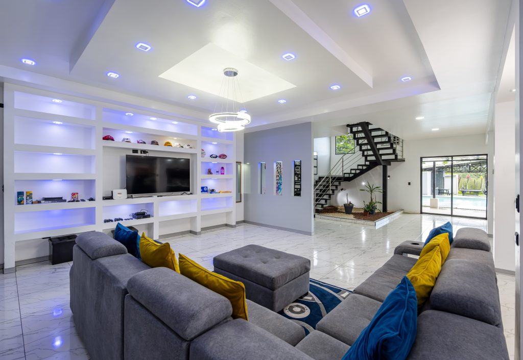 Villa Montreal living room with sectional seating, TV wall, and open staircase in La Fortuna