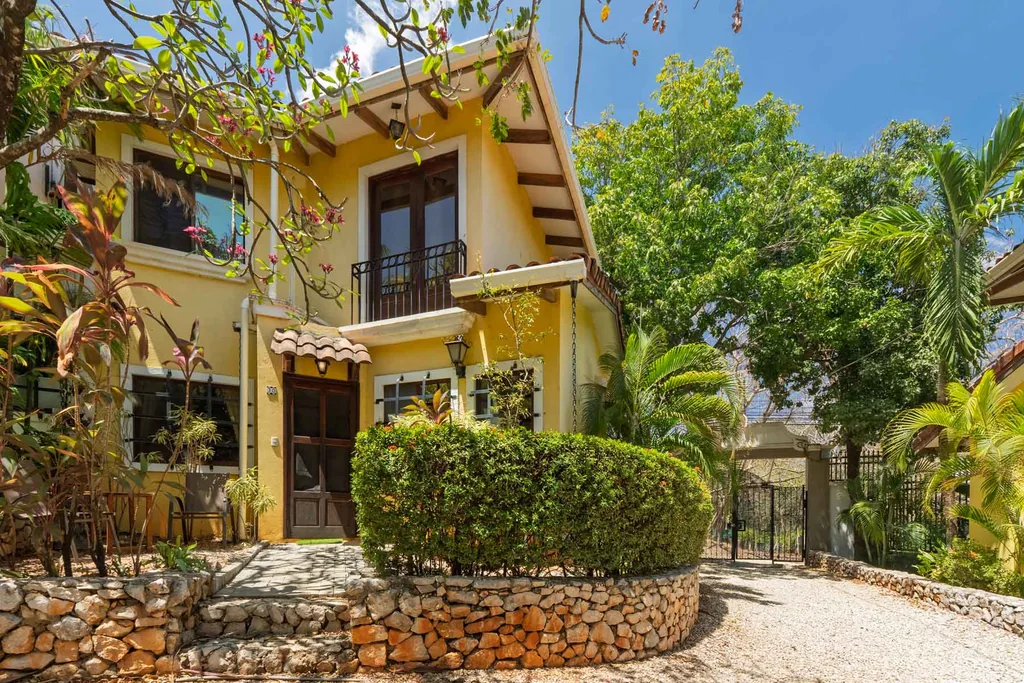 Two-story yellow home with tropical garden and stone entry in Guanacaste, Costa Rica