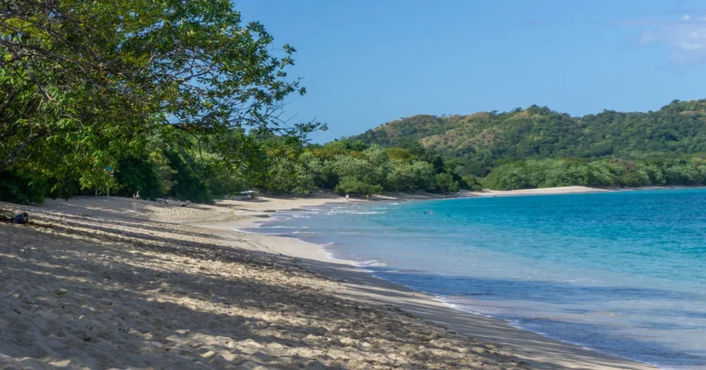 Playa Brasilito beach with white sand, calm turquoise water, and forested green hills, Guanacaste, Costa Rica