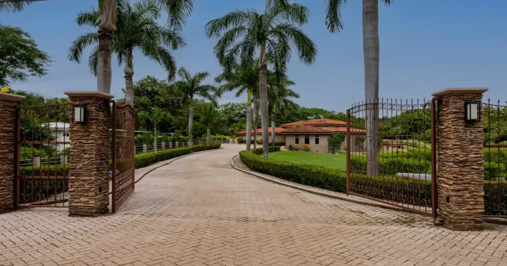 The gated stone entrance to Catalina Cove, with palm-lined driveway and homes beyond, Playa Brasilito, Guanacaste