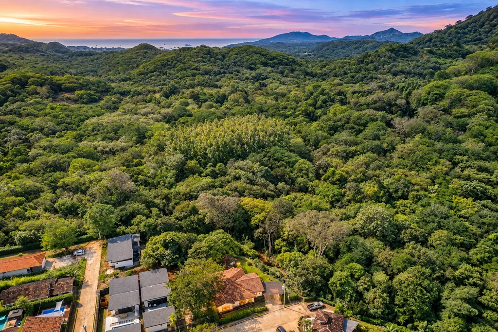 Sunset aerial over the forested hills of Tamarindo, Costa Rica, with the Pacific coast beyond
