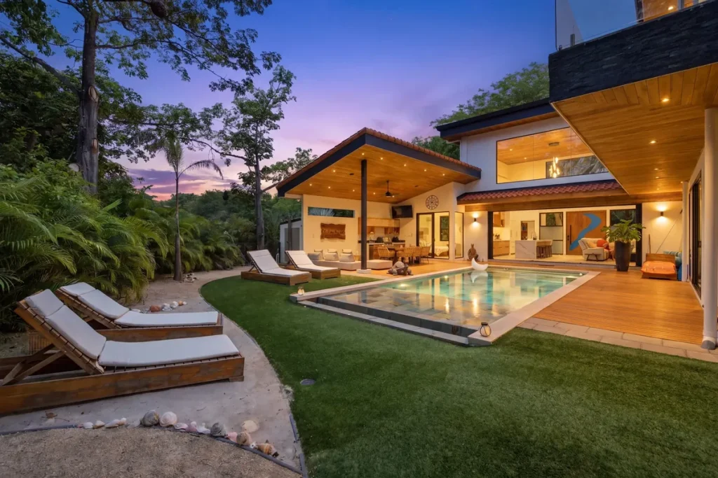 Modern villa with a lit pool and covered terrace at dusk in Hacienda Pinilla, Costa Rica