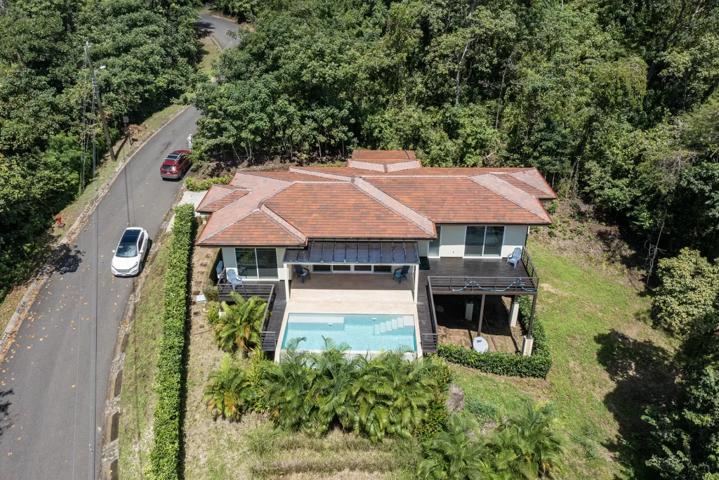 Aerial view of a hillside home with a pool and terraces surrounded by forest in Las Ventanas, near Playa Grande, Costa Rica