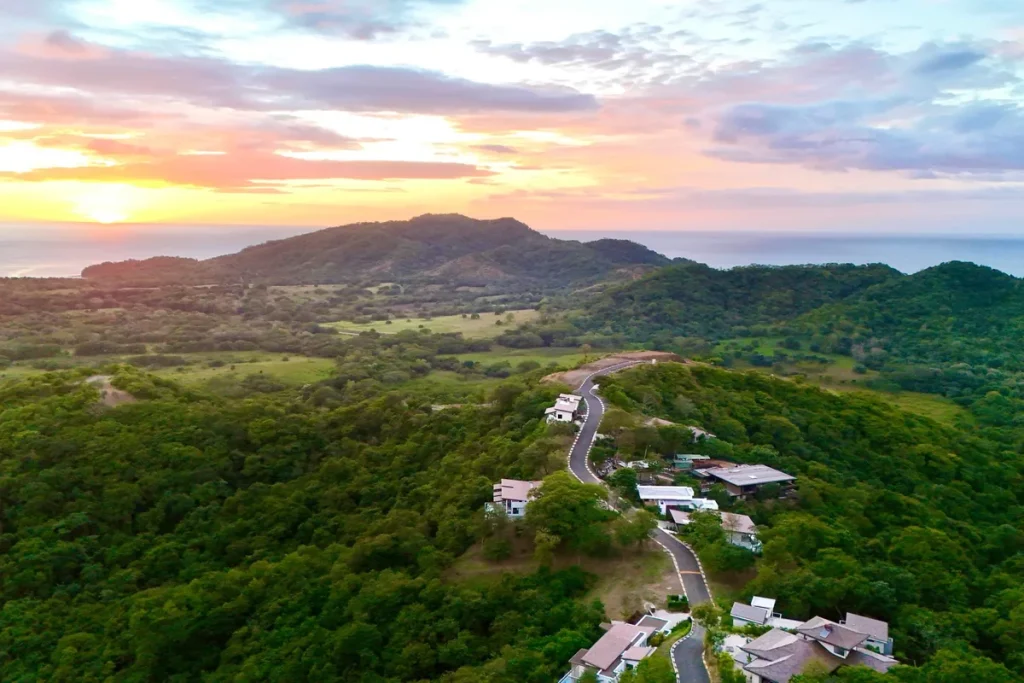 Aerial view of Las Ventanas at sunset, with homes along a hillside road above the Pacific coast near Playa Grande, Costa Rica