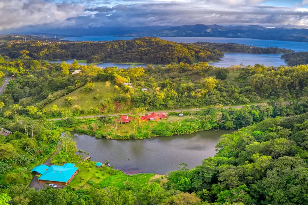 Aerial view of Lake Arenal and green hills near Nuevo Arenal, with homes beside a small lake